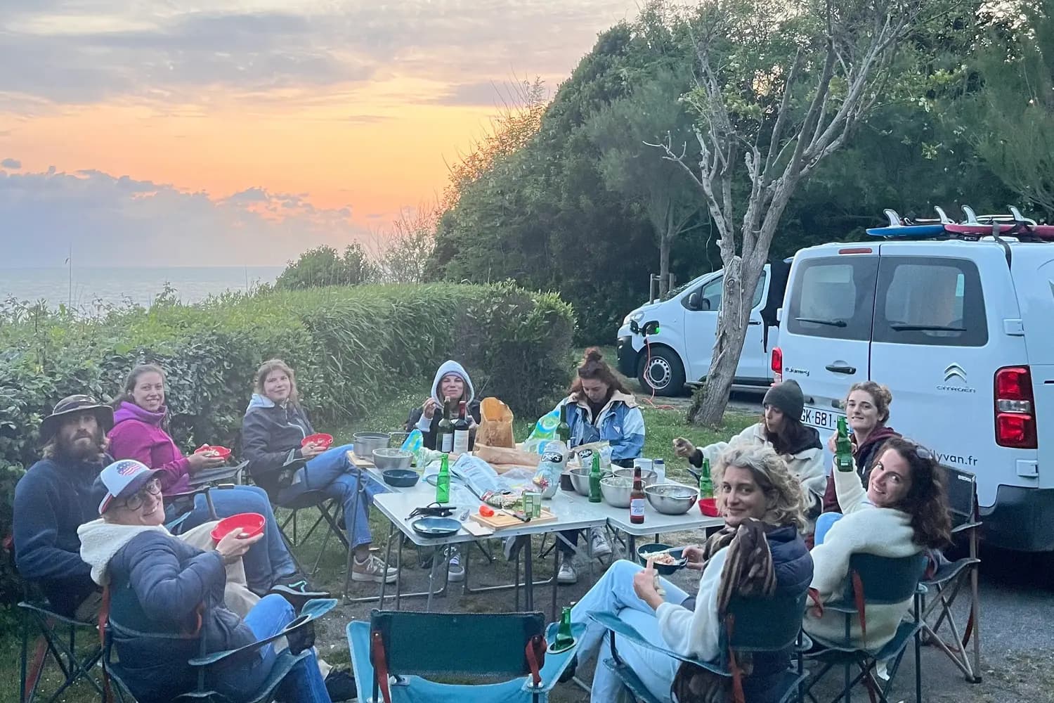 Participants au surfcamp débutant dans le Sud Ouest organisé par The Family Bike en train de dîner au milieu du campement.